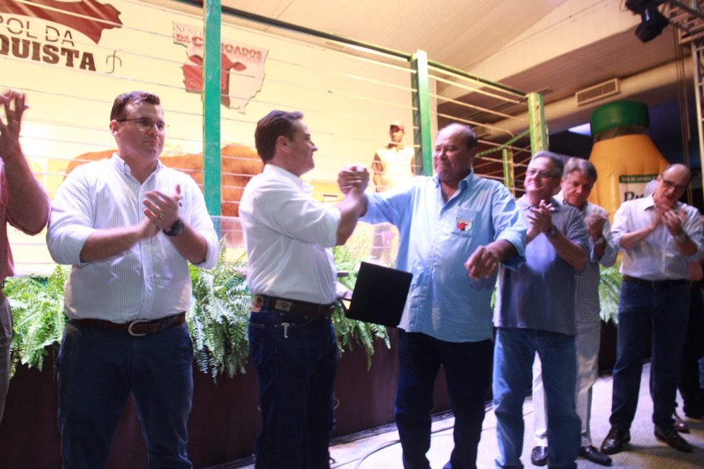 Fábio Mello (esq.) e Jorge Basílio se cumprimentam na abertura do leilão, aplaudidos por dirigentes da Acrimat e Sindicato Rural de Cuiabá. (Foto: Rai Reys)
